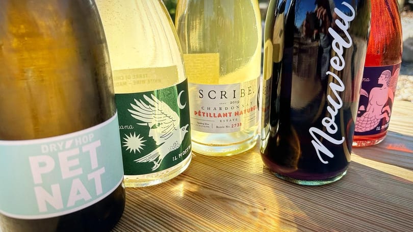 A close-up of five bottles of natural wine, including Pet Nat, Scribe, and Nouveau.