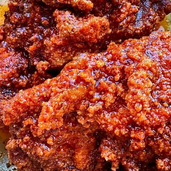 Close-up of crispy, golden-brown fried chicken pieces glistening with a sweet and spicy glaze.