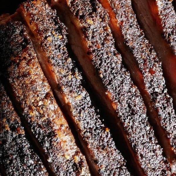 Close-up of perfectly sliced, dark-crusted barbecue brisket with visible seasoning and juicy interior.