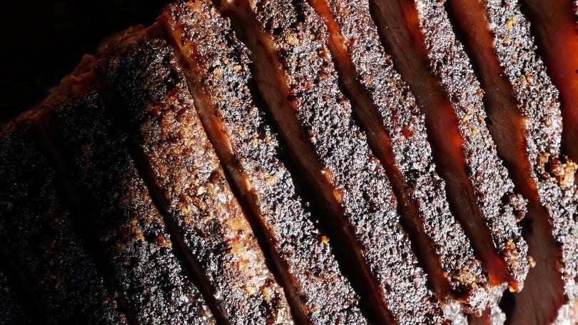 Close-up of perfectly sliced, dark-crusted barbecue brisket with visible seasoning and juicy interior.